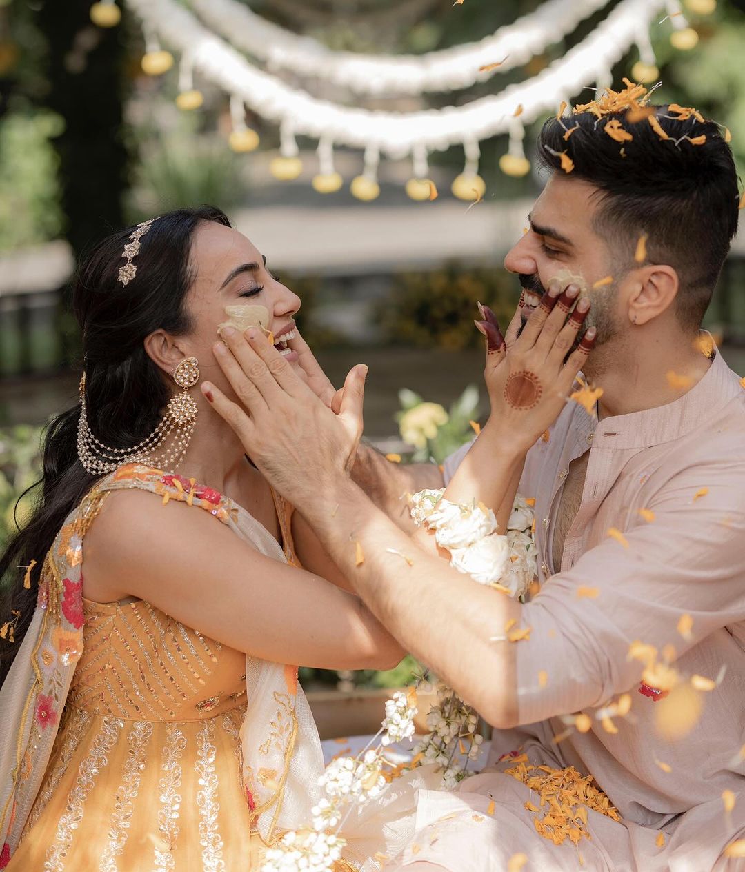 This picture shows the bride and groom posing together as they apply turmeric to each other.