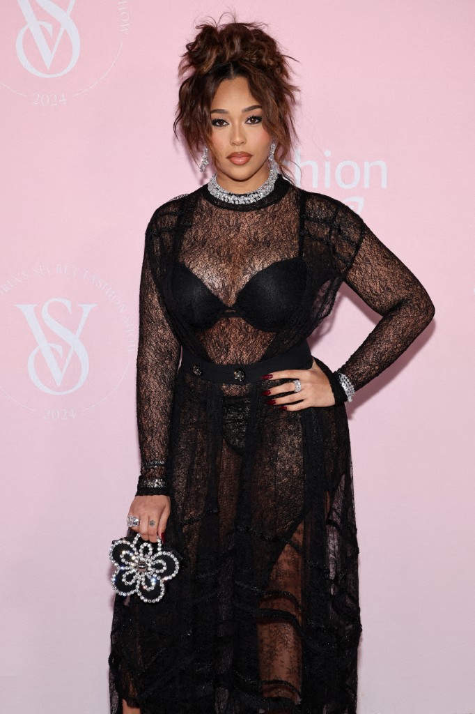 Jordyn Woods made a striking entrance on the pink carpet in a flowing, sheer black gown adorned with intricate swirls of black ribbons.